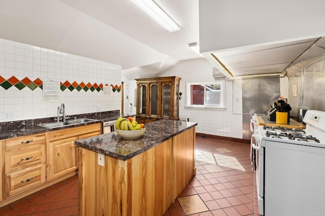 kitchen featuring white gas range, sink, dark stone countertops, and dark tile flooring