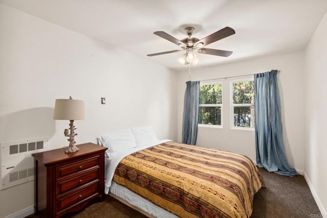 bedroom with dark carpet, ceiling fan, and radiator heating unit