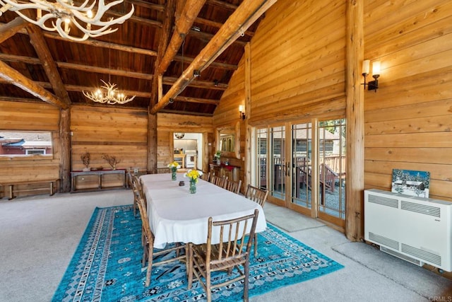 carpeted dining space with wooden walls, lofted ceiling with beams, a chandelier, and wooden ceiling