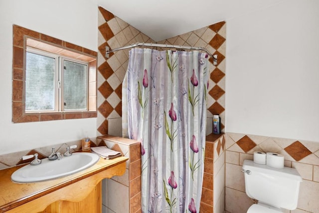 bathroom featuring toilet, vanity, and tile walls