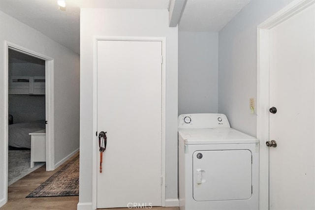 clothes washing area with washer / clothes dryer and light hardwood / wood-style flooring