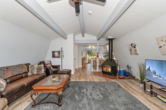 living room with hardwood / wood-style floors, a wood stove, ceiling fan, and lofted ceiling with beams