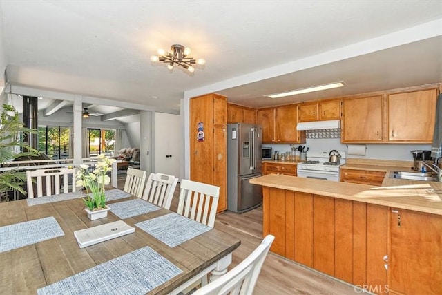 kitchen with high end fridge, white range with gas cooktop, light wood-type flooring, sink, and kitchen peninsula