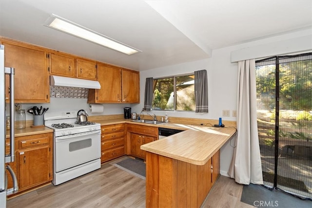 kitchen with light hardwood / wood-style floors, kitchen peninsula, sink, and gas range gas stove