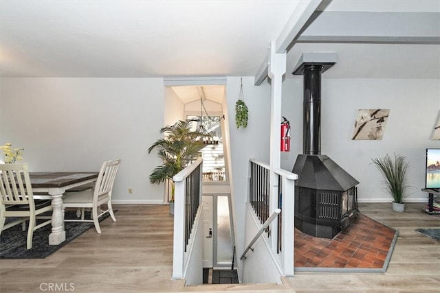 interior space with light hardwood / wood-style flooring, a wood stove, and vaulted ceiling