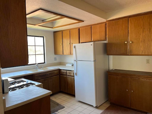 kitchen featuring a textured ceiling, sink, light tile patterned floors, and white appliances