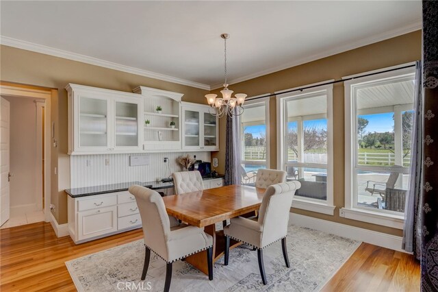 dining space featuring a chandelier, light wood-type flooring, and crown molding