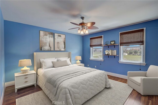 bedroom featuring dark hardwood / wood-style floors, ceiling fan, and multiple windows