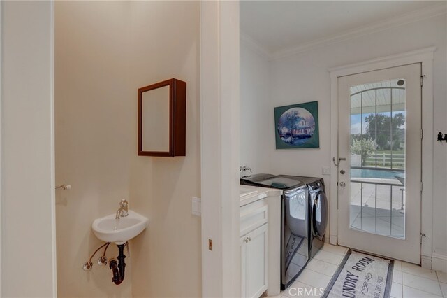 clothes washing area featuring crown molding, washer and clothes dryer, light tile patterned floors, and cabinets