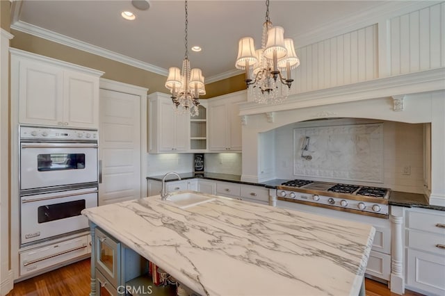 kitchen with hanging light fixtures, white cabinetry, stainless steel gas stovetop, and sink