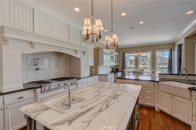 kitchen featuring sink, dark hardwood / wood-style floors, backsplash, dark stone countertops, and crown molding