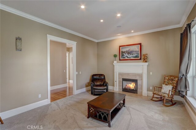 living room featuring a tiled fireplace, light carpet, and ornamental molding