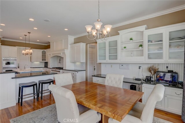 dining space with light hardwood / wood-style floors, ornamental molding, and a chandelier