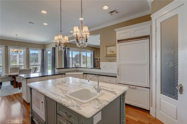 kitchen with a center island with sink, sink, and light hardwood / wood-style flooring