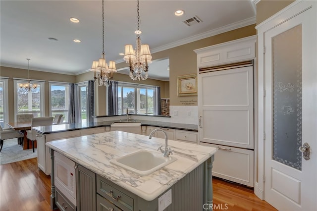 kitchen featuring a chandelier, a kitchen island with sink, and sink