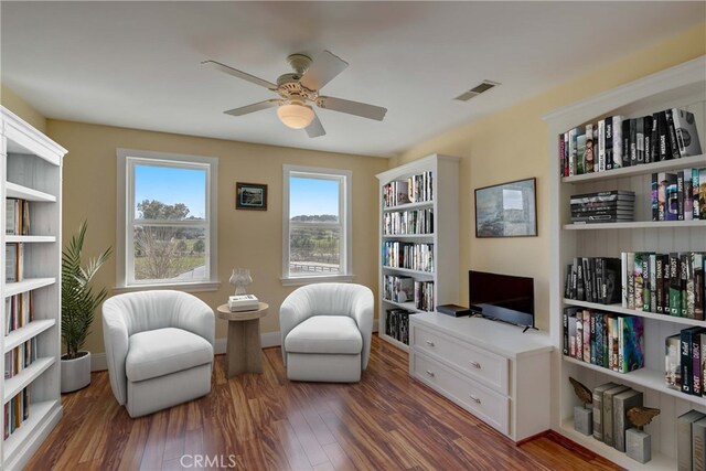 living area featuring ceiling fan and dark wood-type flooring