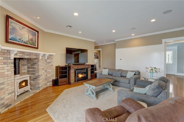 living room featuring a wood stove, crown molding, and light wood-type flooring