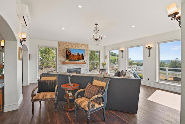 living area featuring a fireplace, dark hardwood / wood-style floors, a wall mounted air conditioner, and plenty of natural light