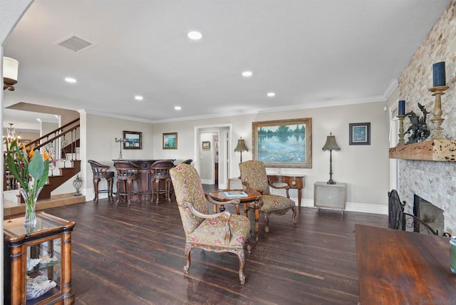 living room with a stone fireplace, crown molding, and dark hardwood / wood-style flooring