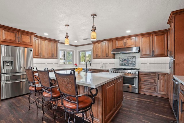 kitchen featuring dark hardwood / wood-style flooring, appliances with stainless steel finishes, hanging light fixtures, and sink