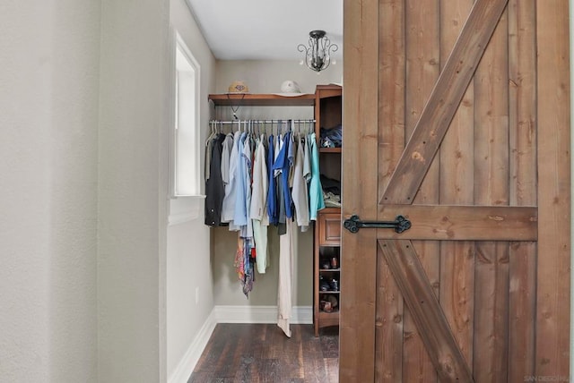 spacious closet featuring a chandelier and dark hardwood / wood-style flooring