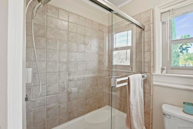 bathroom featuring crown molding, toilet, and a shower with door