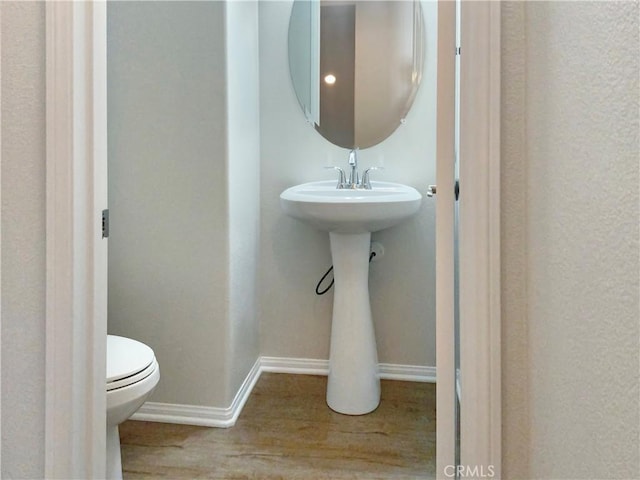 half bath with wood finished floors, toilet, and baseboards