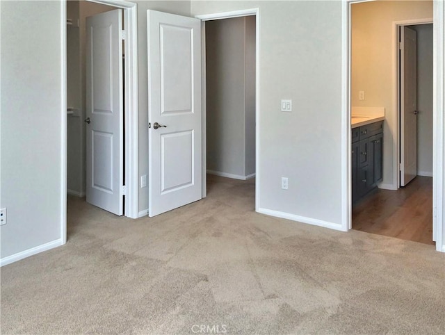 unfurnished bedroom featuring carpet, connected bathroom, a spacious closet, and baseboards