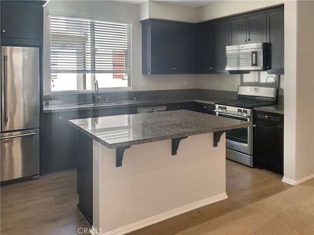 kitchen featuring stainless steel appliances, a breakfast bar, a sink, light wood-type flooring, and a center island