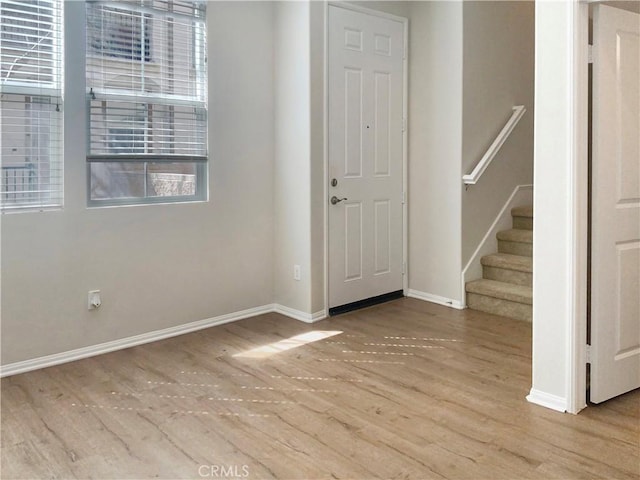 foyer entrance with stairs, baseboards, and wood finished floors