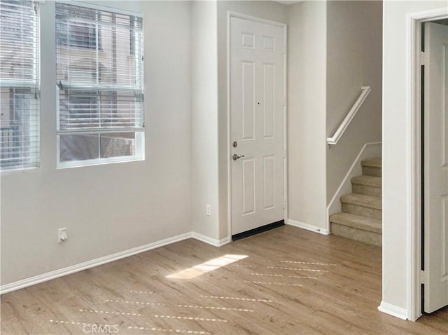 entrance foyer with stairs, baseboards, and wood finished floors