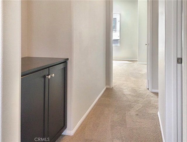 hallway with light colored carpet and baseboards