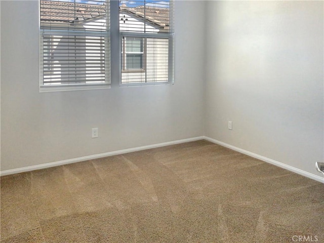 carpeted empty room featuring baseboards