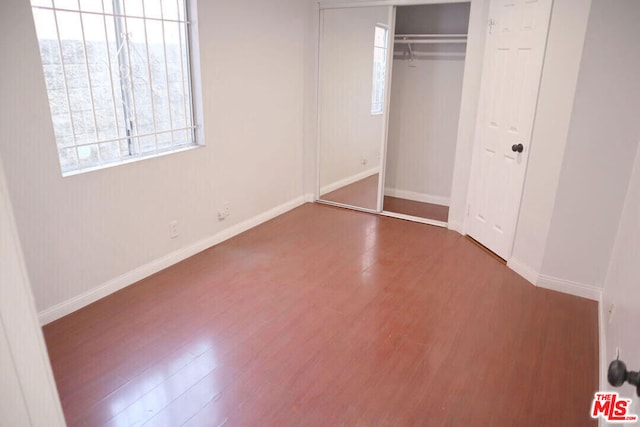 unfurnished bedroom featuring a closet and hardwood / wood-style floors