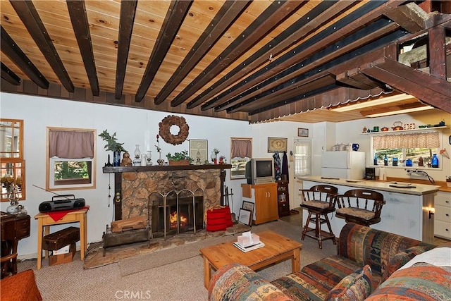 living room featuring beamed ceiling, light colored carpet, wood ceiling, and a fireplace