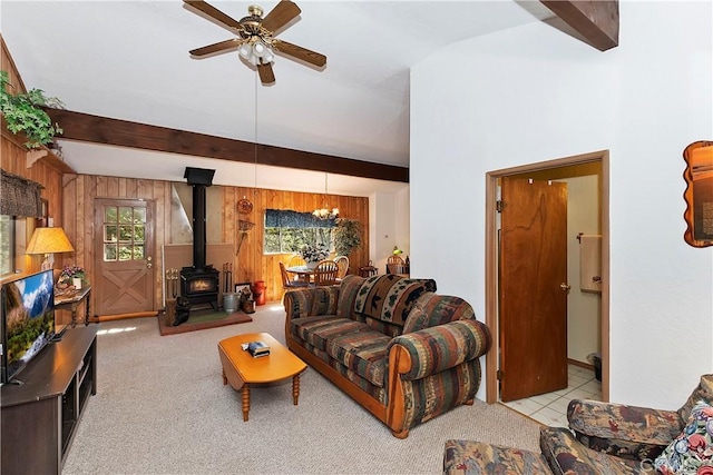 carpeted living room featuring beam ceiling, wooden walls, a healthy amount of sunlight, and ceiling fan with notable chandelier