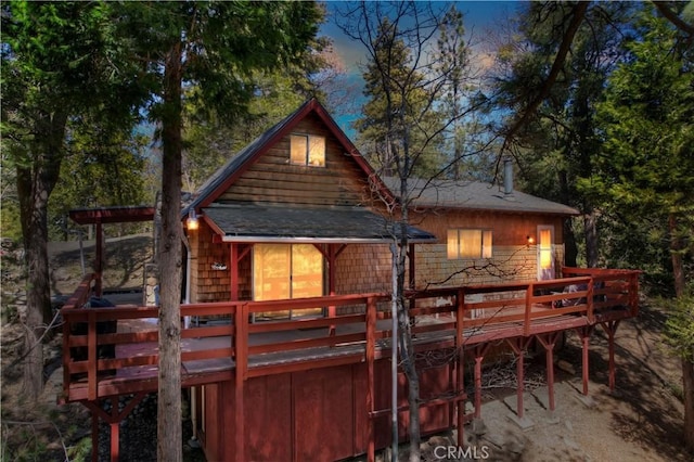 back house at dusk with a wooden deck