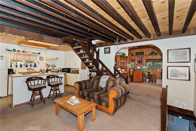 carpeted living room with beam ceiling and sink