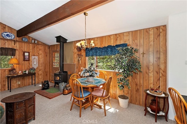 dining space with vaulted ceiling with beams, plenty of natural light, a wood stove, and wooden walls