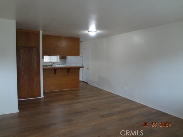 kitchen with kitchen peninsula, dark hardwood / wood-style flooring, white refrigerator, and a breakfast bar area