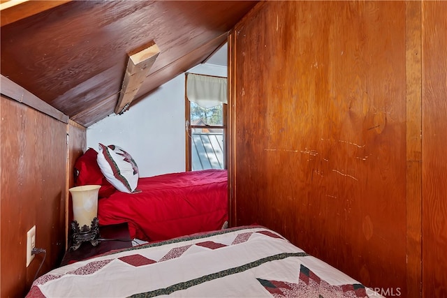 bedroom featuring wooden walls and lofted ceiling