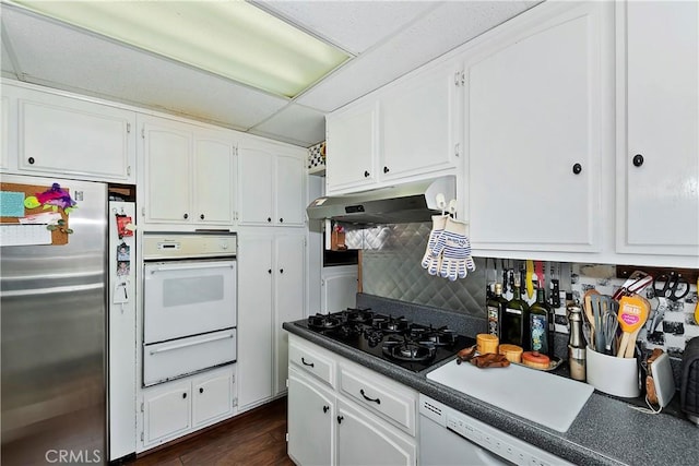 kitchen featuring under cabinet range hood, white appliances, white cabinetry, decorative backsplash, and a warming drawer