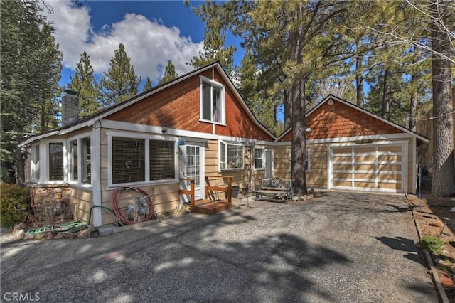 rustic home featuring a detached garage and a chimney