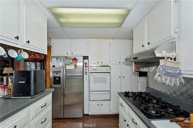 kitchen featuring stainless steel fridge, white cabinetry, dark hardwood / wood-style flooring, oven, and black gas stovetop