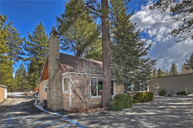 view of front of property featuring a chimney and central AC