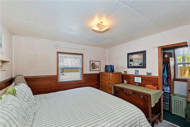 bedroom featuring a walk in closet, a wainscoted wall, wood walls, and carpet flooring