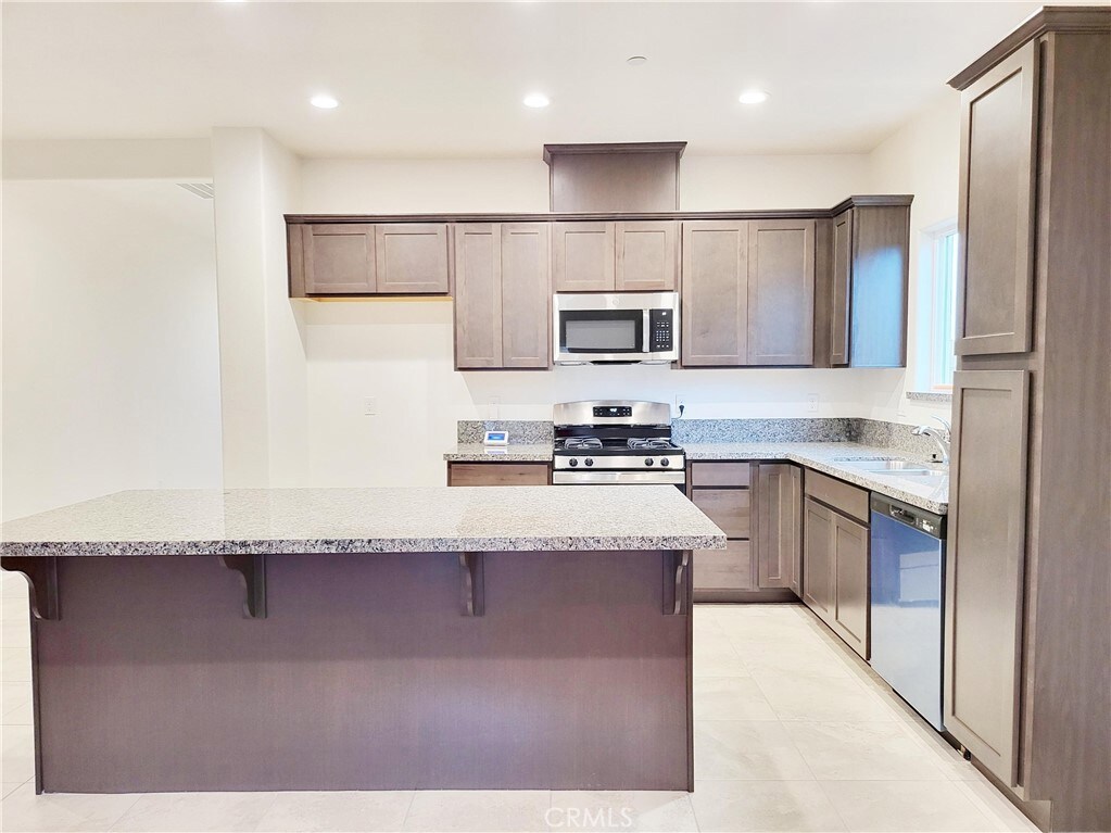 kitchen with a center island, sink, light stone countertops, and stainless steel appliances