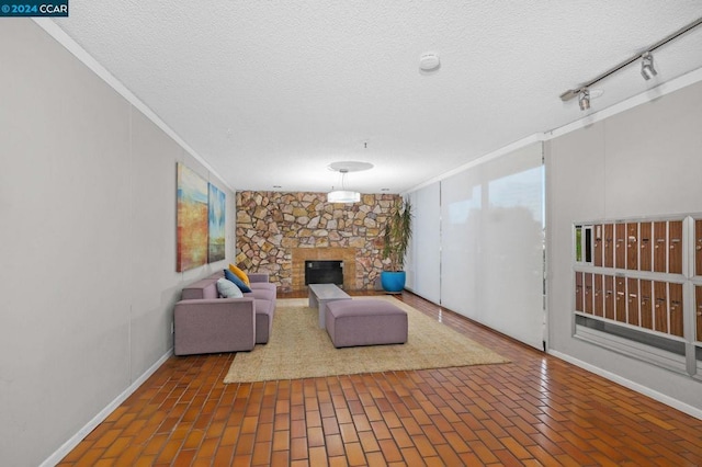 unfurnished living room featuring a stone fireplace, a textured ceiling, and ornamental molding