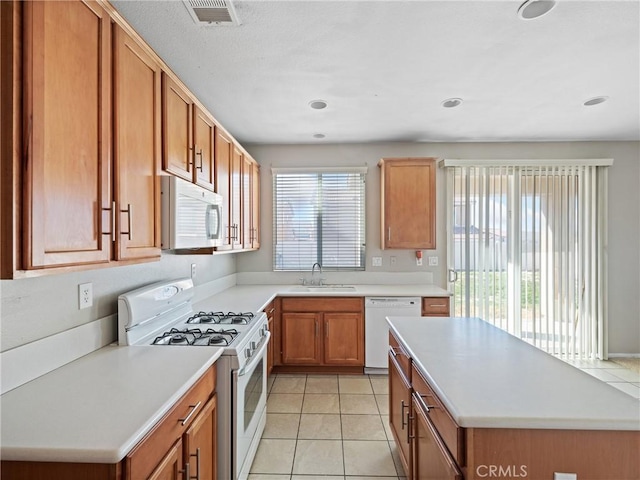 kitchen featuring light tile patterned flooring, white appliances, and sink