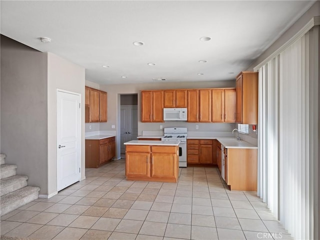 kitchen with a center island, light tile patterned floors, white appliances, and sink